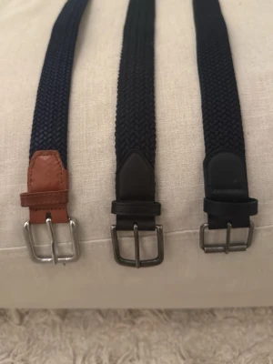3 mörkblå/svarta flätade bälten - Säljer tre väldigt snygga knappt använda bölten passar perfekt till jeans men även till att hålla upp byxorna i skidbacken. Funkar till allt men ger ändå en snygg look. Rekommenderar helt ärligt det själv efter haft de lite. Ett är mer använt än ett annat men själv skulle jag säga att alla är i bra skick. (Ett är inte använt alls tror jag)