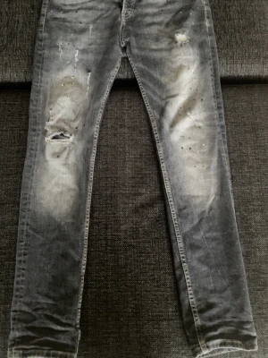 Dsquared jeans - Snygga grå jeans med slitningar, hål på ena benet och blekta detaljer. Jeansen har en sjukt bra passform och klassisk femficksdesign. Perfekta för en trendig och avslappnad stil.