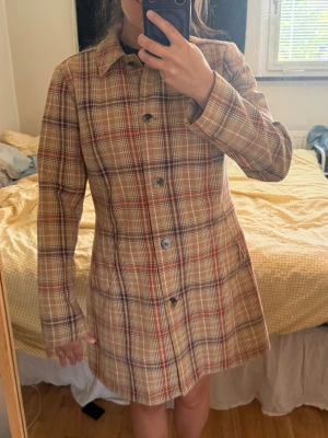 Beige rutig trenchcoat med fickor - Vintage Liz Claiborne long plaid coat, perfect for fall! The colors are tan, brown, purple, orange/ red. In size Large, but could work for medium as well. Outer shell is 85% cotton and 15% wool. Lining is 95% polyester and 5% spandex
