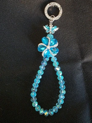 Blått väsksmycke/nyckelring - Unikt handgjort snyggt väsksmycke/armband med glittrande blå pärlor och en stor blomma i mitten. Smycket har silverfärgade detaljer och en dekorativ låsring. Perfekt för dig som gillar färgglada accessoarer och vill sticka ut lite extra.