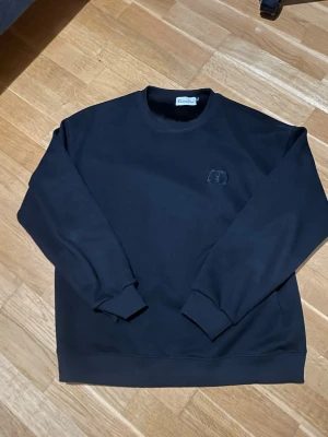 Svart sweatshirt från CD - Säljer en svart sweatshirt från CD med diskret broderad logga på bröstet. Tröjan har rund halsringning, långa ärmar och ribbade muddar vid ärmslut och nederkant. Tillverkad i mjukt material som känns skönt mot huden. Komm med bud vid snabb affär. Står storlek xl men skulle säga att det är m