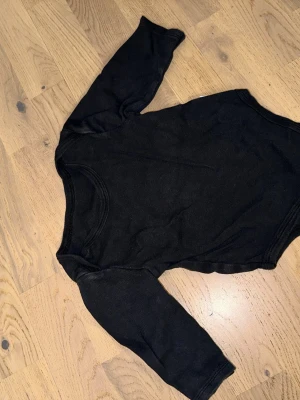 Svart långärmad body i bomull - Svart långärmad body i bomull En enkel och stilren svart body med långa ärmar, tillverkad i 100% bomull. Perfekt för lager på lager och riktigt skön mot huden. Klassisk rund halsringning och mjukt material.