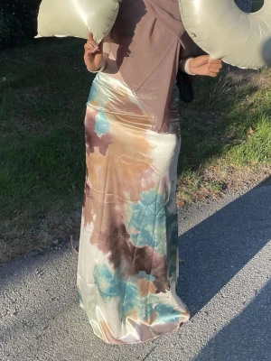 Maxi kjol i satin med akvarellmönster - ANVÄNT 2 ggr, mycket fint skick!! Elegant kjol i glansigt satinmaterial med ett unikt akvarellinspirerat mönster i toner av beige, blått, brunt och turkos. 