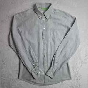 Eton Slim skjorta grå storlek S / 38 / 15 - Stilren ljusgrå skjorta från Eton i Slim Fit. Tillverkad i 100% bomull med klassisk krage och bröstficka. En tidlös skjorta som passar både till arbete, kontor och mer uppklädda tillfällen.  Storlek S / 38 (15) Slim Fit  Mycket fint skick.  Mått Bröstbredd: ca 51 cm Plagglängd: ca 70 cm Axelbredd: ca 44 cm Ärmlängd: ca 65 cm  Material 100% bomull  Klassisk krage, bröstficka och ljusgrå melerad väv.  Tycker du priset är för högt? Skicka ett prisförslag!