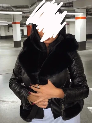 Svart skinnjacka med stor fuskpälskrage - Snygg svart skinnjacka med stor fluffig fuskpälskrage och huva. Jackan har dragkedja framtill, quiltade detaljer på ärmarna och en markerad midja. Jackan är varm och kan bäras på vintern.   Jackan är från femenina of Sweden och i jätte fint skick. Endast använd vid ett tillfälle.  Bilder tagna från nätet, vid fler bilder är det bara att skriva 💕