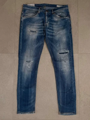 DONDUP Jeans - En snygg ljusblå tvätt av den dyrare modellen med färgstänk från populära märket dondup. Dondup är ett väletablerat märke inom grischkulturen och söljs vanlitvis för 6-700kr på andrahandsmarknaden. Produkten har tydliga tecken på användning men har använts av mig i detta skick och de otiltänkta slitagen finns på tacksamma ställen och har inte påverkat upplevelsen.