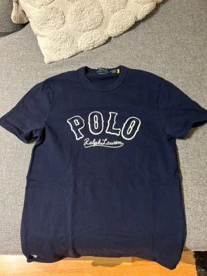 Mörkblå Polo Ralph Lauren t-shirt - Snygg mörkblå t-shirt från Polo Ralph Lauren med vit broderad logga på bröstet. Modellen är custom slim fit och har klassisk rund hals och korta ärmar. Perfekt för dig som gillar stilrena och tidlösa plagg.
