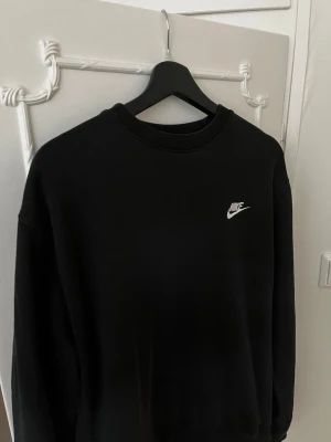 Svart sweatshirt från Nike - Säljer en svart sweatshirt från Nike med klassisk vit logga på bröstet. Relativ ny, införköpt på stadium -1000kr, Perfekt för en avslappnad och sportig stil. Materialet känns mjukt och bekvämt mot huden.