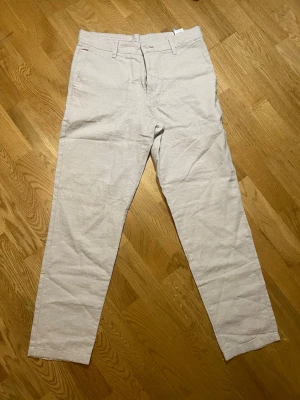 Beige linnebyxor Cubus - Säljer ett par snygga beige linnebyxor från Cubus i storlek S med raka ben och klassisk passform. Byxorna har hällor för skärp, knapp och dragkedja framtill samt sidofickor. Perfekta för en avslappnad och stilren look. Vid frågor, extra bilder eller liknande är det bara att kontakta mig!