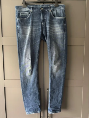 Blå Slim Dondup George  - Ett par fräscha och nästintill splitternya Dondup Georges med ljusa slitningar och klassisk femficksdesign. Jeansen har normal midja, raka ben och subtila detaljer på bakfickorna. Tillverkade i denim med en skön stretch för extra komfort. Köpta i butik för 2799kr(se bild 4) storlek=Mindre i storlek i verkligheten än vad som står 