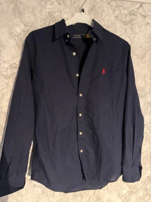 Mörkblå Linneskjorta Ralph Lauren - Tjena, säljer nu en mycket fin mörkblå linneskjorta från Ralph Lauren, den är använd några gånger och har inga defekter. Storlek S men passar även M, har du någon fundering är de bara att skriva och ge gärna prisförslag!!