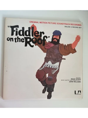 Fiddler on the Roof - Original Motion Picture Soundtrack Recording (Dubbel-LP) - Detta är soundtrack-albumet från originalfilmen "Fiddler on the Roof" (Spelman på taket) från 1971. Det är en "Deluxe 2 Record Set" (dubbel-LP) med inbyggt häfte med bilder, utgiven av United Artists Records. Musiken är adapterad och dirigerad av John Williams, med Isaac Stern som soloviolinist. Perfekt för dig som gillar musikalhistoria och samlarobjekt.