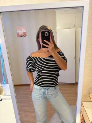 ONLY Randig offshoulder topp svart/vit - Snygg offshoulder topp med svarta och vita ränder. Toppen har korta ärmar, ribbad struktur och en liten knytning i ryggen. Perfekt för dig som vill ha en trendig och bekväm look med lite edge. L men sitter som M