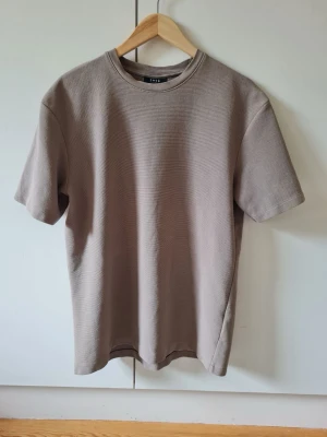 Beige t-shirt Relaxed fit från SMOG strl S - Säljer en beige t-shirt från SMOG (New Yorker).  Material 78% bomull, 22% polyester. Storlek S.