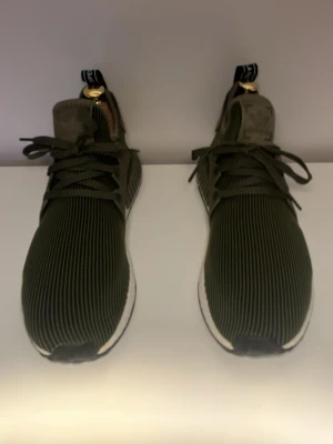Olivgröna sneakers med ribbad ovandel - Snygga sneakers i olivgrönt med ribbad textilovandel och vita sulor. Skorna har svarta detaljer, breda skosnören och en modern siluett. Perfekta för dig som gillar streetwear och vill ha något unikt på fötterna. Pris kan diskuteras.