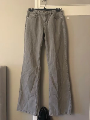 Gråa utsvängda jeans från NA-KD - Säljer ett par gråa jeans från NA-KD i storlek 34. Jeansen har utsvängda ben och klassisk femficksdesign. Perfekta för dig som gillar en trendig och avslappnad look. Materialet är denim i bomull.