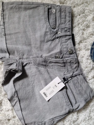 Grå lågmidjade denimshorts  - Säljer ett par gråa lågmidjade denimshorts  Shortsen har bälteshällor, knappgylf och bakfickor. Oanvända, prislapp kvar💕