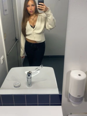 Krämvit kofta från Gina Tricot - Säljer en krämvit kofta från Gina Tricot med rund halsringning och silvriga knappar framtill. Koftan har en avslappnad passform och långa ärmar. Perfekt att styla med ett linne under för en trendig look.