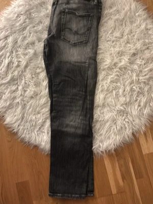 Grå snygga jeans från Jack & Jones - Snygga grå jeans från Jack & Jones cool look. Klassisk femficksmodell med detaljerade sömmar på bakfickan. Perfekta för en avslappnad och trendig stil.