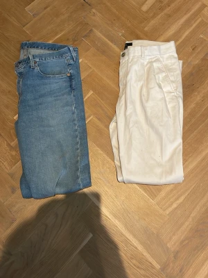Blå raka jeans med klassisk passform - Säljer två par jeans. Det blå jeansen är ett par Levi’s 501 i storlek W31 L34. Väldigt bra skick. De vita jeansen är från HM i storlek 30. Också i väldigt bra skick! Kom med prisförslag🙌