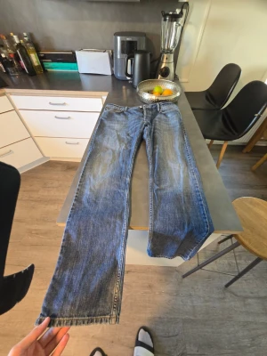 Blå raka jeans från Burberry - Säljer ett par klassiska blå jeans från Burberry med raka ben och snygga slitningar. Jeansen har detaljer i metall och en läderpatch med Burberry-logga bak. Perfekta för dig som gillar tidlös stil och kvalitetsmaterial.