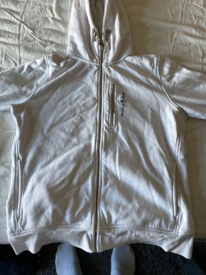 Vit Sail Racing hoodie med dragkedja - Vit hoodie från Sail Racing i storlek XL som har krympt vilket gör att det passar large/medium. Hoodien har söndrig dragkedja framtill, samt lite småfläckar här och där men ingenting som syns jättetydligt. 