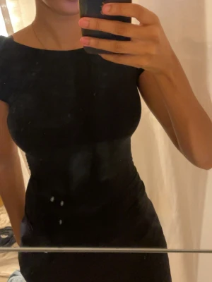 Svart tight topp med öppen rygg - Säljer en svart, tight topp med korta ärmar och en riktigt snygg öppen rygg. 