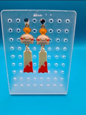 Färgglada anime-inspirerade örhängen - Örhängen i form av Chimecho med nickelfria krokar. Ca 5cm långa.
