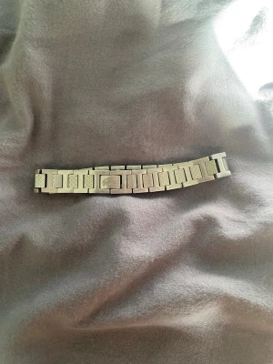 Silverfärgad länkarmband till klocka - Snyggt länkarmband i silverfärg till klocka. Armbandet har en klassisk design med rektangulära länkar och en smidig låsmekanism. Perfekt för dig som vill byta ut eller uppgradera din klocka med en stilren metallänk.