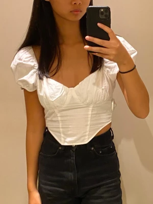 Vit croppad blus med puffärmar - Snygg vit croppad blus med puffiga korta ärmar och fyrkantig urringning. Lite korsettliknande design skulle jag säga. Även om den är i 38/M passade den mig när jag hade 36/S. 