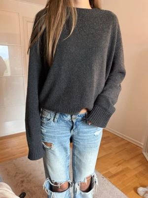 Mörkgrå oversized stickad tröja - Mysig mörkgrå stickad tröja med oversized passform och breda ribbade muddar vid ärmslut och nederkant. Tröjan har rund halsringning och är tillverkad i ett mjukt material som passar perfekt för kyligare dagar.