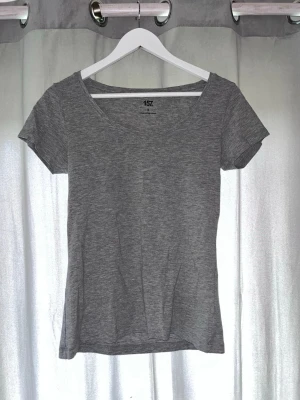 Grå basic t-shirt från 157 - En enkel och stilren grå t-shirt från 157 i mjuk bomullsblandning. T-shirten har rund halsringning och korta ärmar, perfekt för en clean och avslappnad look. Materialet är 61% bomull, 34% viskos och 5% elastan.