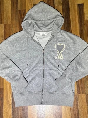 Ami Paris grå zip hoodie - Jag säljer en grå Ami Paris zip hoodie. Använd fåtal gånger. Väldigt bra skick. Storlek medium i herr men sitter som small. Kontakta vid frågor eller funderingar.