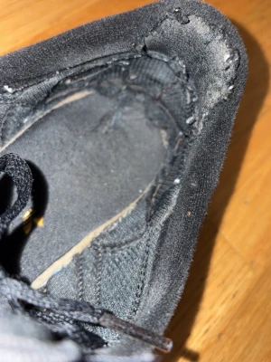 Svarta Adidas sneakers med vita ränder - Klassiska svarta Adidas La trainers sneakers med tre vita ränder på sidan och gula detaljer vid hälen. Skorna har snörning och är tillverkade i en kombination av mocka och textil. Snygg retrostil som passar till jeans och streetwear men även träning.
