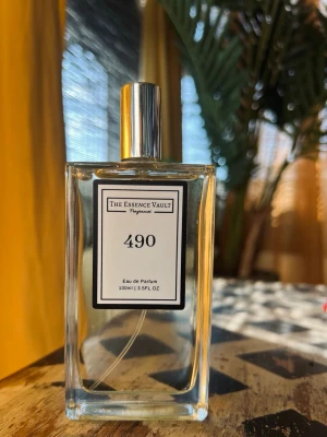 The Essence Vault 490 EdP, 100ml - Säljer en stilren parfym från The Essence Vault, nummer 490. Flaskan är rektangulär i genomskinligt glas med silverfärgad spraykork och lock. Innehåller 100 ml Eau de Parfum. Enkel och modern design som passar perfekt på parfymhyllan. Bara testad, som ny. 