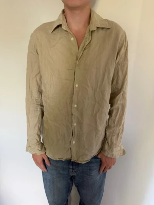 Beige långärmad linneskjorta från Jack & Jones - Säljer en beige skjorta i linne med lång ärm och klassisk krage. Skjortan har knappar framtill och en avslappnad passform. Från Jack&Jones, storlek M men det passar på mig som bär storlek L. Hör av dig om du har några frågor eller vill ha fler bilder. Pris kan diskuteras!  