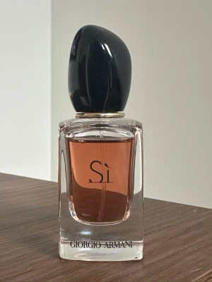 Giorgio Armani Sì Eau de Parfum - Elegant parfymflaska från Giorgio Armani med svart lock och transparent glas. Flaskan har stilren design med texten 'Sì' på framsidan. Använd endast litegrann som man kan se på bilden.  