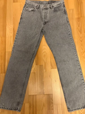Grå raka jeans med hög midja - Säljer ett par grå jeans med rak passform och hög midja. Klassisk femficksmodell med bälteshällor och dragkedja. Jeansen är i ett mjukt denimtyg och har en vintagekänsla som passar till allt.