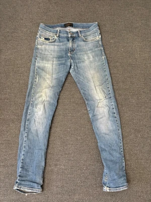 J.Lindeberg Jeans - Säljer ett par ljusblå slim fit jeans med slitningar och tvättade detaljer från J.Lindeberg. Jeansen har klassisk femficksmodell, normalhög midja och smala ben. Perfekta för en avslappnad och trendig look. Skick 7,5/10🙌
