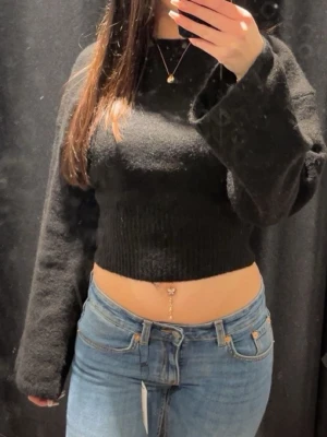 Svart croppad stickad tröja - Säljer en svart croppad stickad tröja från Gina tricot med långa, vida ärmar och ribbad midja. Den är använd men i perfekt skick.