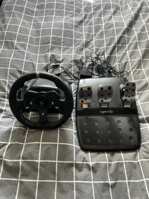 Logitech ratt och pedaler Xbox/PC - Säljer en Logitech ratt och pedalset för Xbox och PC. Ratten är svart med metallinslag och har gummiklädd yta för bra grepp. Pedalerna är i svart plast och metall, med gas, broms och koppling. Perfekt för racing- och bilspel!