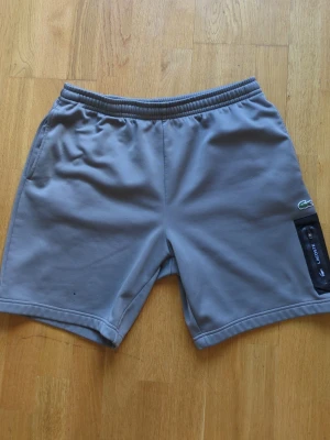 Lacoste shorts - Lacoste shorts i okej skick. Har tre pyttesmå brännhål i ena benet, märks knappt. Köptes på JD Sports för 899kr. Säljes för 300kr prutat och klart. Storlek L. Tvättas innan köp.