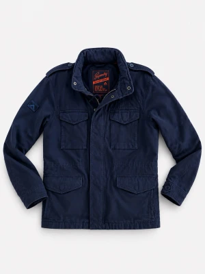 Marinblå fieldjacket från superdry - Snygg marinblå vindjacka med fyra framfickor, axelklaffar och hög krage. Jackan har dragkedja och tryckknappar framtill samt detaljer på ärmen. Perfekt för dig som vill ha en stilren och funktionell jacka till vardags.