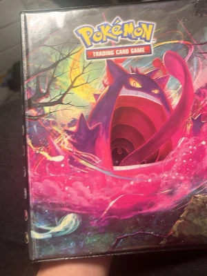 Pokémon TCG samlarpärm med kort - Säljer en Pokémon Trading Card Game samlarpärm med färgglad framsida och flera holografiska kort, bland annat M Ampharos EX, M Charizard EX och två M Venusaur EX. Perfekt för dig som vill utöka din Pokémonkort-samling med coola och glansiga kort.