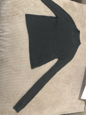 Mörkgrå ribbstickad tröja - En enkel och stilren mörkgrå ribbstickad tröja med lång ärm och rund halsringning. Tröjan har en smal passform och är perfekt för lager-på-lager. Materialet är mjukt och följsamt.