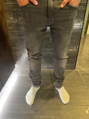 Blend  - Säljer ett par grå slim fit jeans med klassisk femficksdesign och dragkedjegylf. Jeansen har en snygg tvättad look och smal passform som sitter tajt längs benen. Perfekta för en trendig och avslappnad stil.