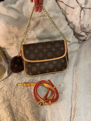 A monogram-patterned bag - A monogram-patterned bag in excellent condition, used only a couple of times. It comes with a detachable long strap and a small coin purse/mini pouch for small items. The bag can be worn as a handbag, a shoulder bag, or crossbody. The interior features a zippered pocket and an open pocket. Closure via zipper and snaps. Color: brown/monogram pattern with gold-tone hardware. Clean inside.