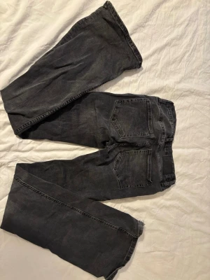 Svarta bootcut jeans - Säljer ett par svarta jeans med klassisk femficksdesign och utsvänga ben. Jeansen har en diskret patch bak i midjan och är tillverkade i ett slitstarkt denimtyg. Perfekta för dig som gillar en enkel och tidlös stil.