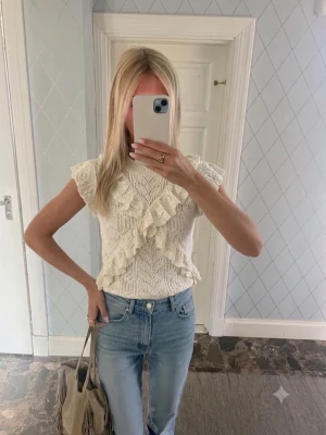 Beige spets topp med volanger - Supersöt beige topp med spetsdetaljer och volanger. Croppad modell med korta ärmar och v-ringning. Perfekt för dig som gillar romantisk och feminin stil.
