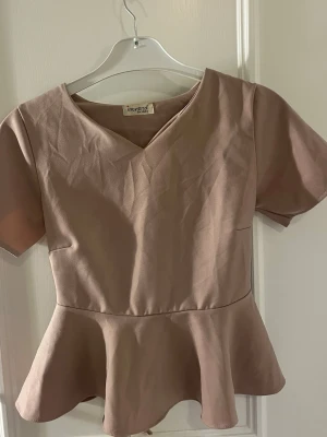 Gammelrosa topp med knytband i ryggen - Söt gammelrosa topp med v-ringning och korta ärmar. Toppen har ett  knytband i ryggen så man kan knyta en söt rosett 🎀Toppen är mer rosa i verkligheten än på bilden. Den saknar även storlekslapp men skulle säga att de är storlek  Xs eller eventuellt S